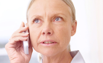 Female Doctor with concern on her face while holding her cell phone up to her ear.
